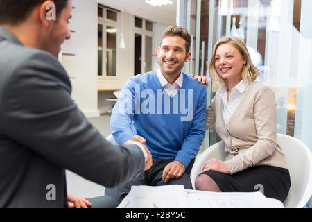 Geschäftsmann Händeschütteln mit paar im Büro Stockfoto