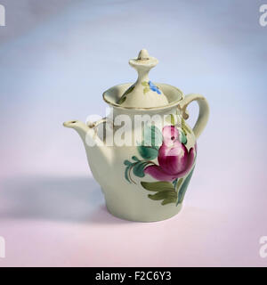 Weiße Teekanne aus Porzellan mit bemalter lila Blume an der Seite Stockfoto