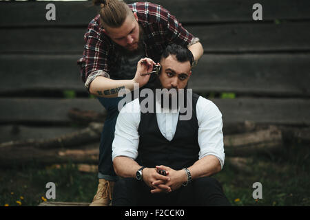 Barbier rasiert ein bärtigen Mannes Stockfoto