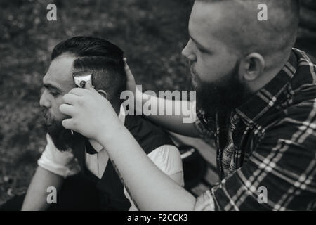 Barbier rasiert ein bärtigen Mannes Stockfoto