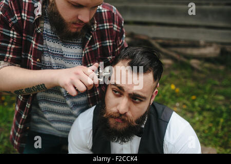 Barbier rasiert ein bärtigen Mannes Stockfoto