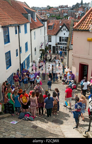 Church Lane, an der Basis der 199 Stufen, mit einem Chor singen im Vordergrund.  Whitby, Yorkshire, England, UK Stockfoto