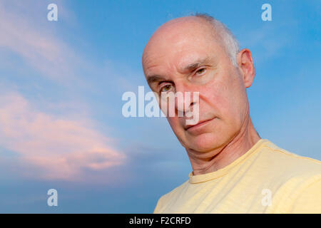 Ein senior Mann posiert mit nachdenklichen, ernst und albern Ausdrücke im Freien vor einem blauen Himmel. Stockfoto