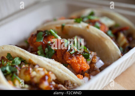 Diagonale Seitenansicht von drei verschiedenen Tacos in einem offenen Behälter zum mitnehmen Stockfoto