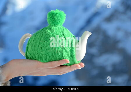 Teekanne in der geknoteten Kappe in der Hand Againstmountain Landschaft Stockfoto