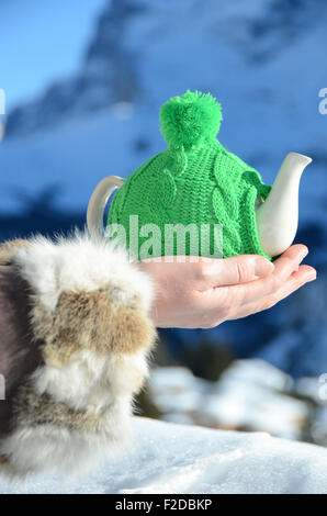 Teekanne in der geknoteten Kappe in der Hand Againstmountain Landschaft Stockfoto