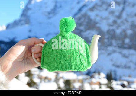 Teekanne in der geknoteten Kappe in der Hand Againstmountain Landschaft Stockfoto