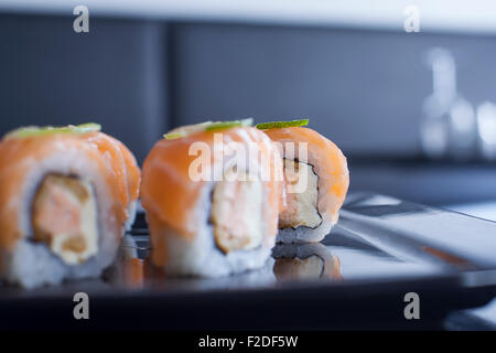 Sushi-Rolle mit Frischkäse und gebratenen Lachs. Garniert mit rohen Lachs und Kalk. Hautnah. Stockfoto