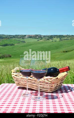 Rotwein auf dem karierten Stoff gegen die toskanische Landschaft. Italien Stockfoto
