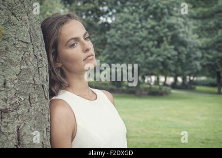 traurige junge Frau lehnte sich gegen Baum-retro-Stil Stockfoto