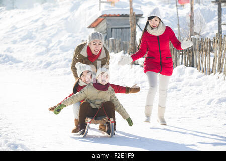 Glückliche Familie mit Schlitten im Schnee spielen Stockfoto