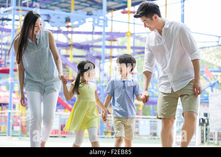 Glückliche junge Familie im Freizeitpark spielen Stockfoto