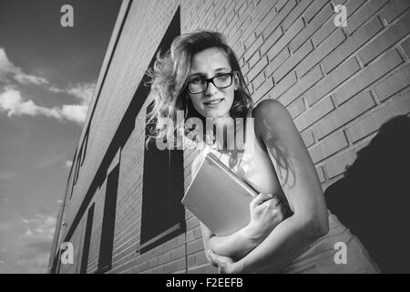 Porträt von Studentin außerhalb Bibliothek neben der Mauer Stockfoto