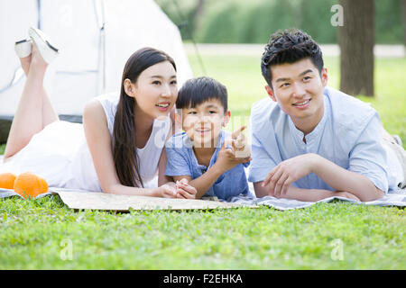 Glückliche junge Familie liegen auf dem Rasen Stockfoto