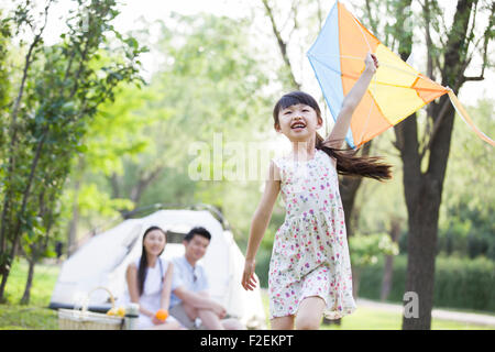Glückliche Mädchen laufen auf dem Rasen mit einem Drachen Stockfoto