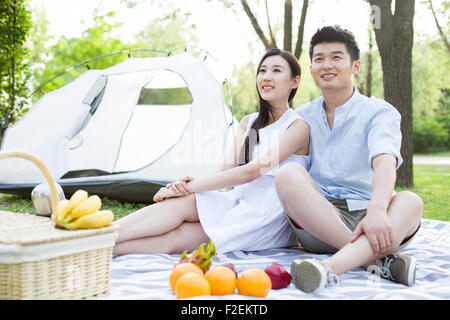 Glückliches junges Paar mit Picknick auf dem Rasen Stockfoto