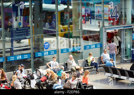 Manchester Piccadilly Station Bahnfahrgäste in der Bahnhofshalle mit He-Zug durch er sichtbar Glas Passagiere vorbei an P Stockfoto