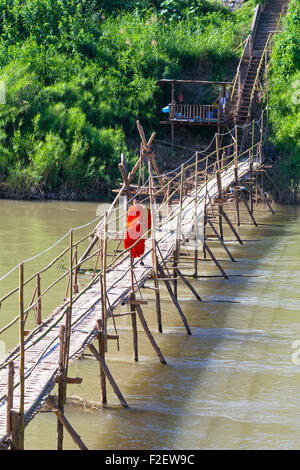 Mönch auf Fußgängerbrücke über Nam Khan Fluss, Luang Prabang, Laos Stockfoto