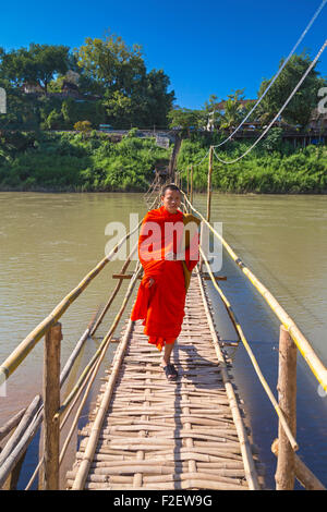 Mönch auf Fußgängerbrücke über Nam Khan Fluss, Luang Prabang, Laos Stockfoto