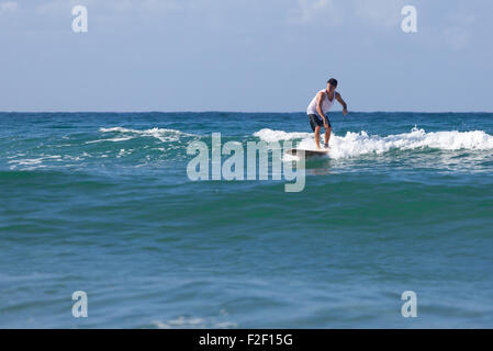 Surfer auf Longboard reitet eine schöne blaue Welle im Meer. Stockfoto