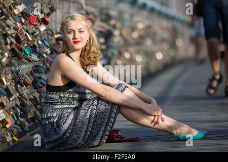 Hübsche junge Frau sitzt auf der Brücke der Liebe in Krakau. Stockfoto