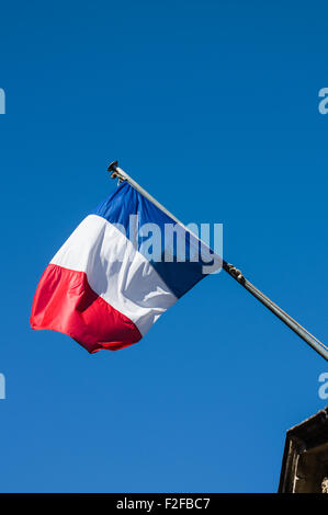 Französische Flagge gegen blauen Wolkenhimmel auf Straße Stockfoto