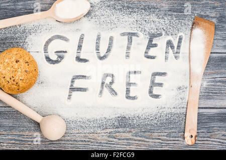 Gluten freies Wort geschrieben am Mehl. Tisch aus Holz Hintergrund. Stockfoto