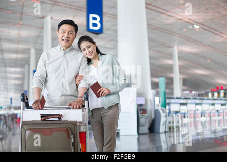 Älteres Paar zu Fuß in Flughafen mit Koffer Stockfoto