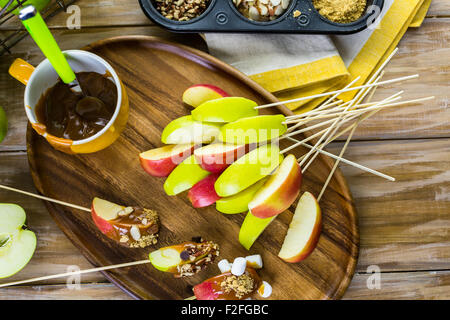 Apfelscheiben in Karamell getaucht und mit verschiedenen Belägen bedeckt. Stockfoto