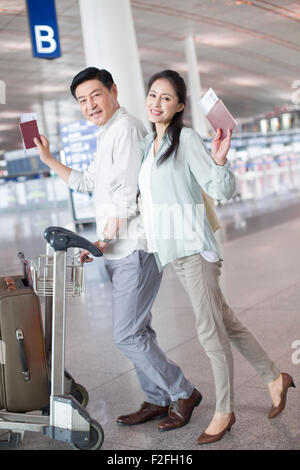 Älteres Paar zu Fuß in Flughafen mit Koffer Stockfoto