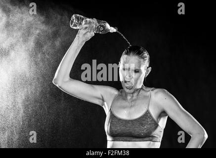 Sportliche Frau gießt Wasser über Kopf müde Stockfoto
