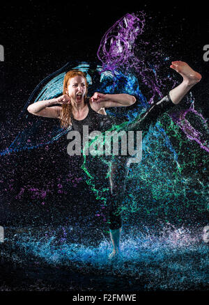 Frau hoch treten in bunten Wasser spritzt Stockfoto