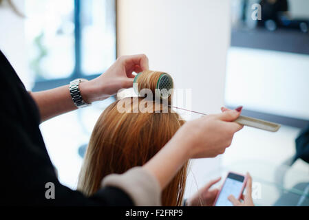 Umhüllung des Kunden Haar in Lockenwicklern im Salon Friseur Stockfoto