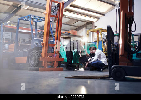 Mechaniker arbeiten in der Nähe von Gabelstapler in Autowerkstatt Stockfoto