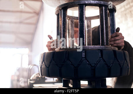 Mechaniker mit Reifen Maschine in Autowerkstatt Stockfoto