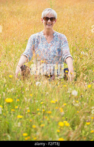 Porträt senior Frau sitzt mit gekreuzten Beinen im ländlichen Bereich Stockfoto
