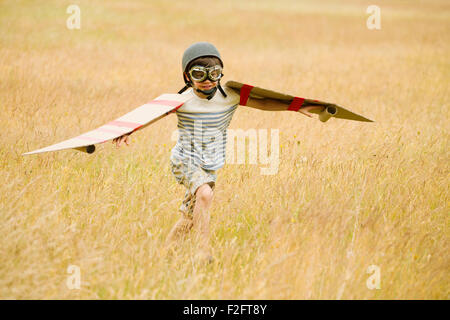 Junge läuft mit Flügeln und Flieger Mütze und fliegenden Brille im Bereich Stockfoto
