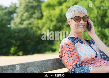 Lächelnd senior Frau am Handy im park Stockfoto