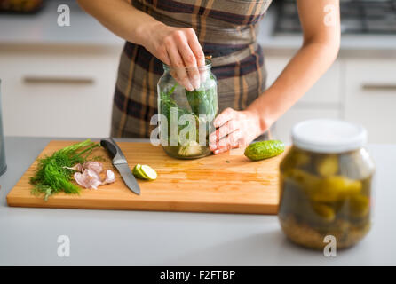 Schritt für Schritt kommen die Aromen zusammen. Hier sind eine Frauenhand hart bei der Arbeit, Gurken und Dill in Essig einlegende Glas Füllung, wie sie selbstgemachte Dill Pickles bereitet. Stockfoto