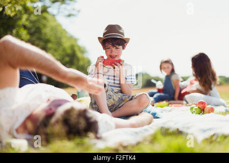 Lächelnde junge Essen Wassermelone auf Decke in sunny Feld Stockfoto