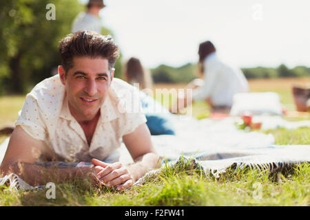 Lächelnder Mann Porträt Handauflegen Picknickdecke im sonnigen Feld Stockfoto