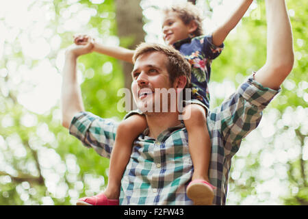 Vater mit Sohn auf Schultern unter Bäumen Stockfoto