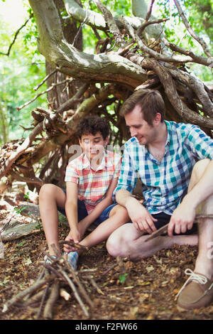 Vater und Sohn machen kleine Lagerfeuer mit Stöcken im Wald Stockfoto