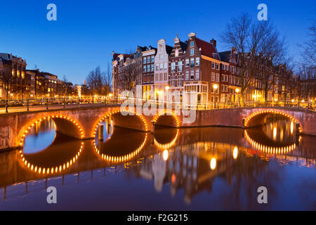 Brücken über eine Kreuzung der Kanäle in der Stadt Amsterdam, die Niederlande in der Nacht. Stockfoto