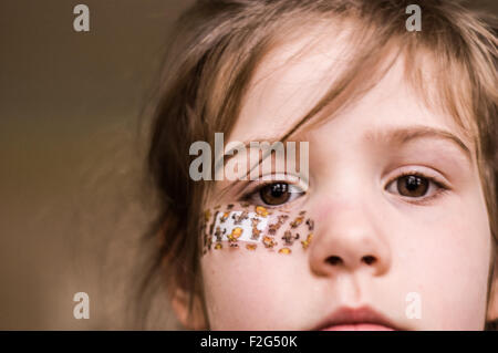 Ein intensiver Blick durch ein schönes junges Mädchen mit einem Pflaster im Gesicht Stockfoto