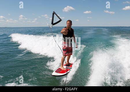 Ein Mann wirft das Abschleppseil zurück zum Boot beim Wakesurfen. Stockfoto