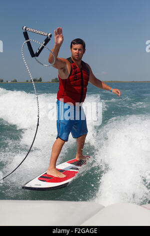 Ein Mann wirft das Abschleppseil zurück zum Boot beim Wakesurfen. Stockfoto