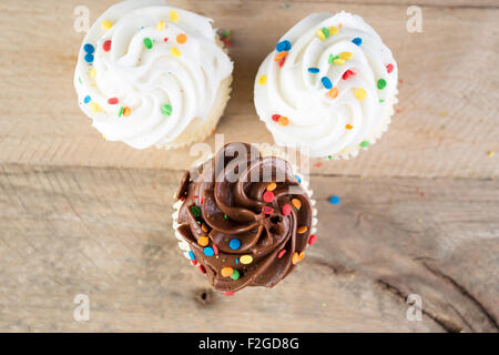 Hausgemachte weiße und Schokoladen Cupcakes verwitterte Holz Hintergrund. Stockfoto