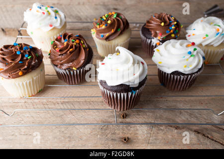 Hausgemachte weiße und Schokoladen Cupcakes verwitterte Holz Hintergrund. Stockfoto