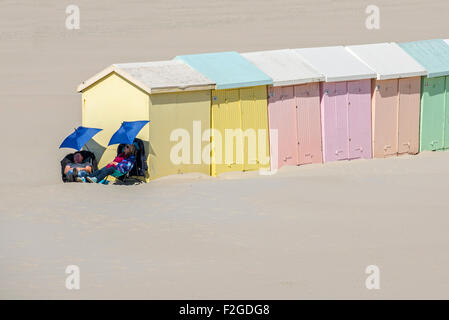 Zweitägige Ausflügler schlafend unter Sonnenschirmen neben Pastellfarben Strand Hütten / Hütten, Berck / Berck-Sur-Mer, Côte d ' Opale, Frankreich Stockfoto